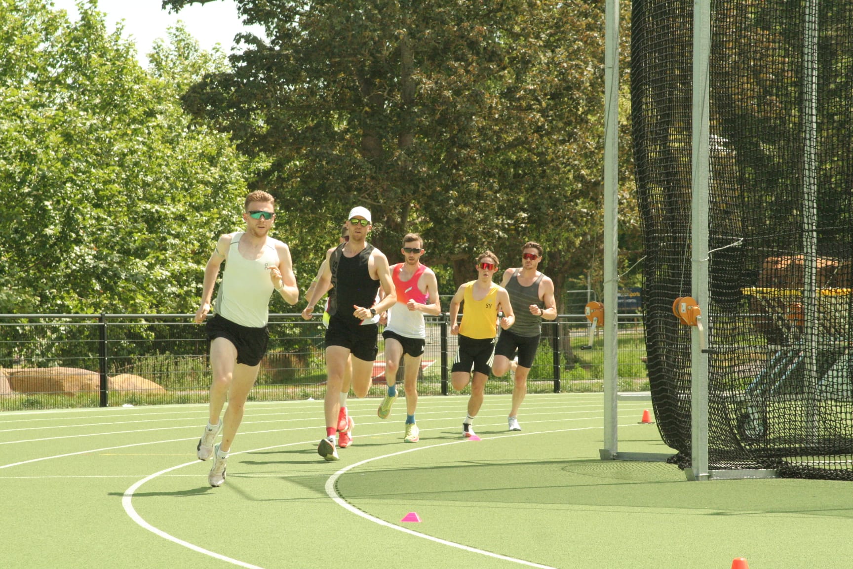 Endurance athletes running together around a bend during a track session